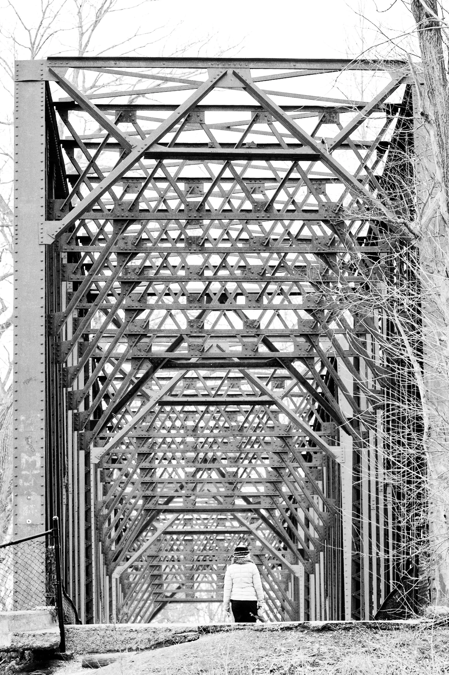 Brand & location — person at entrance of steel truss bridge, bare winter trees