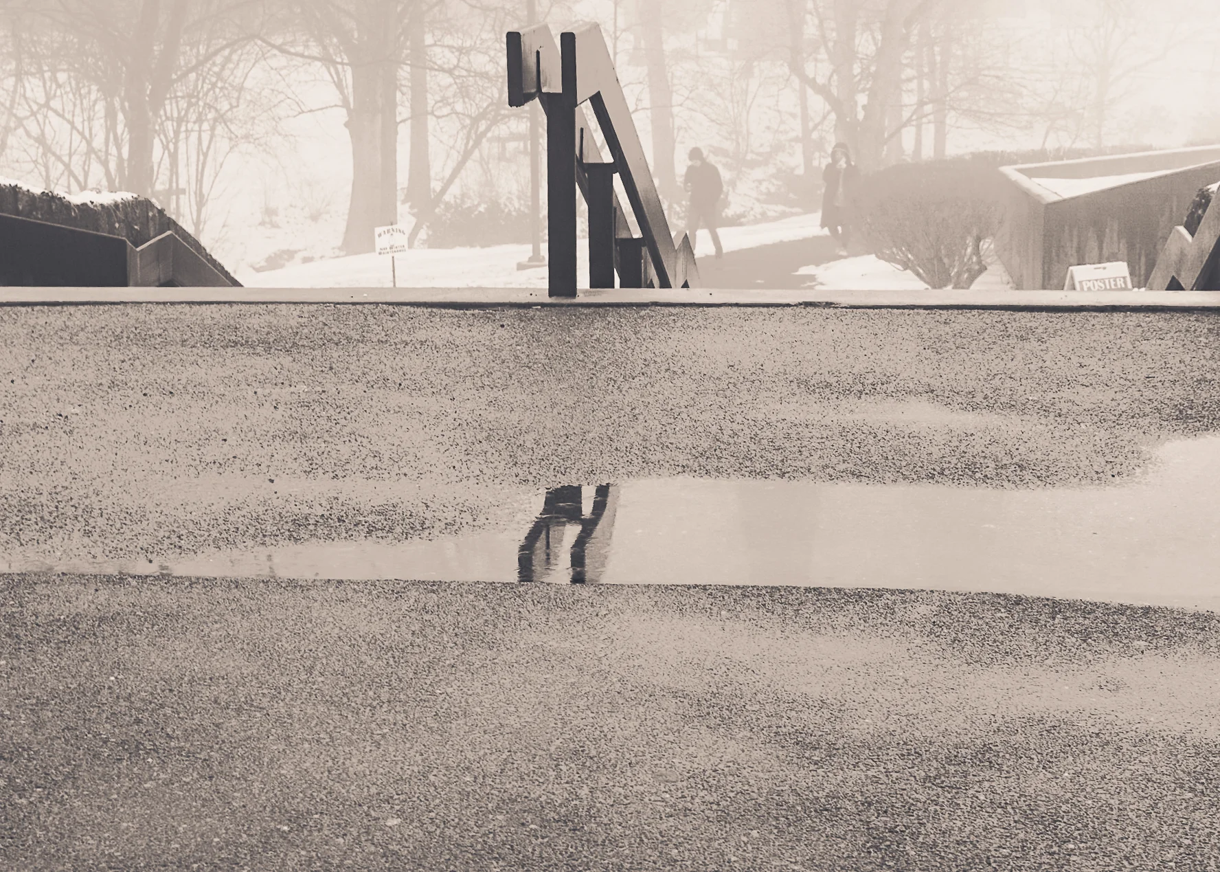 Brand & location — figure reflected in wet surface, foggy winter campus