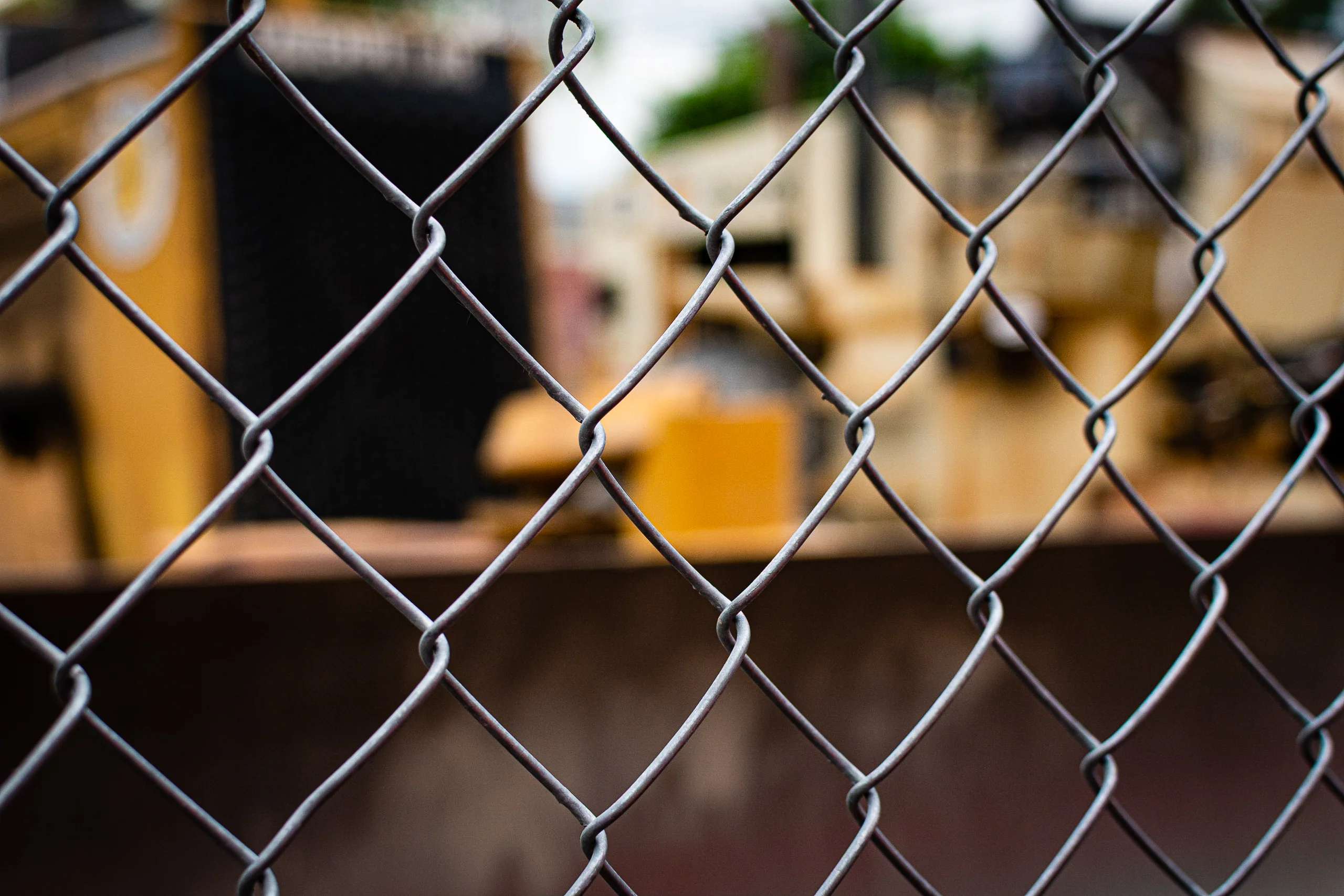 Brand & location — chain-link fence, yellow construction equipment behind