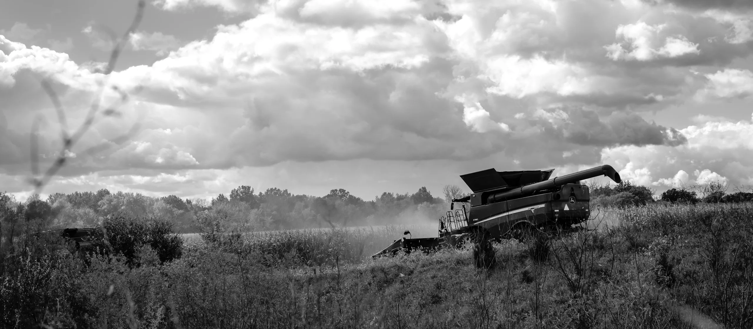 Brand & location — combine harvester in field under dramatic storm clouds