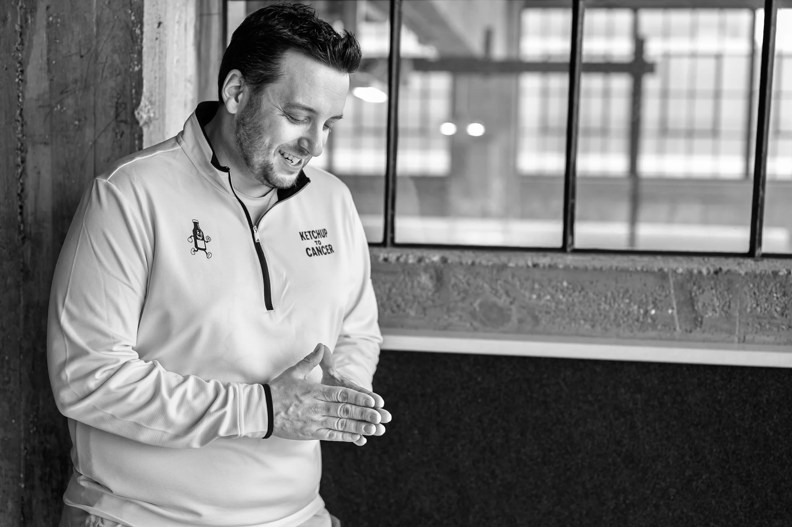 Brand & location — man in branded jacket, laughing, industrial window