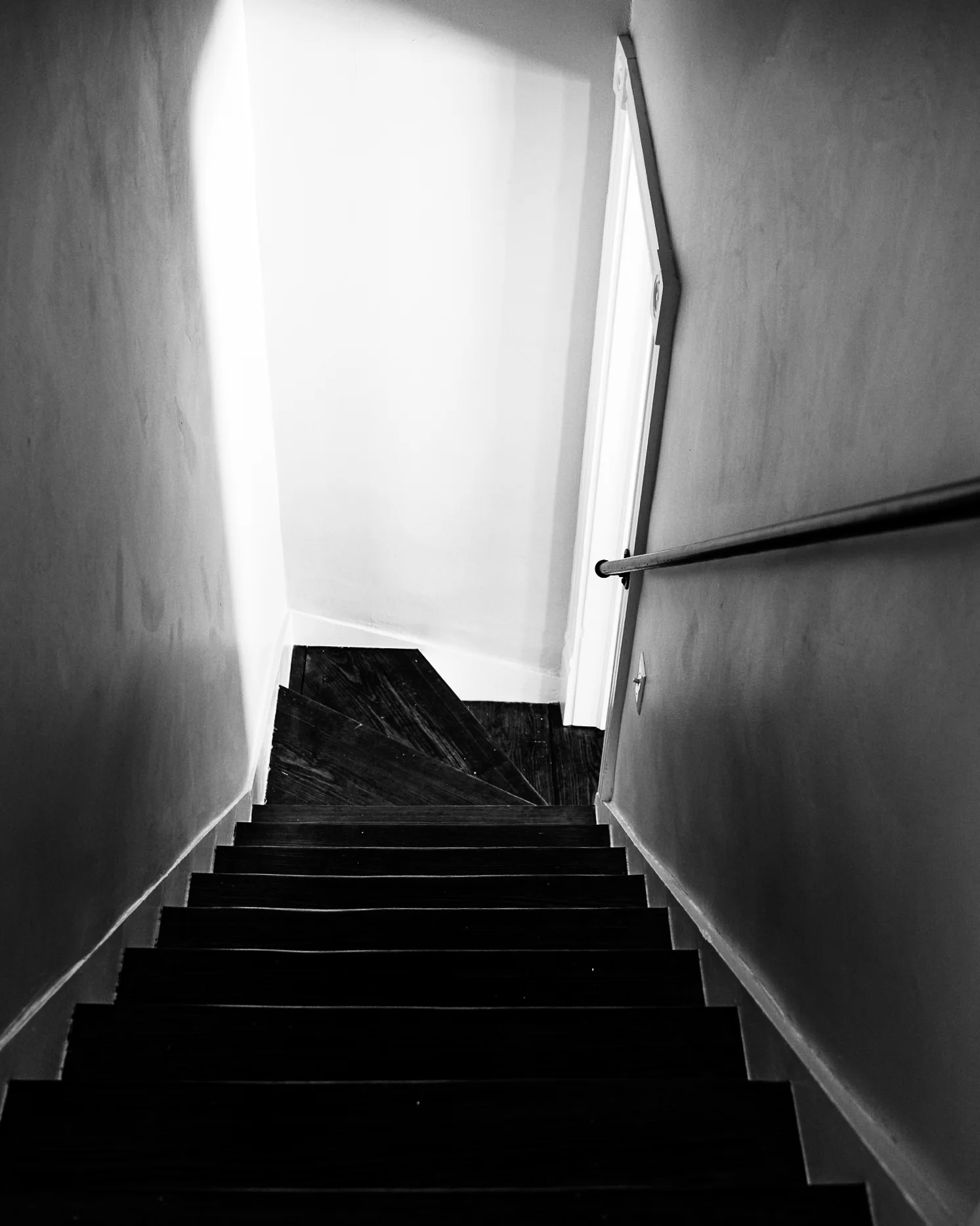 Brand & location — dark staircase looking toward bright doorway, dramatic light