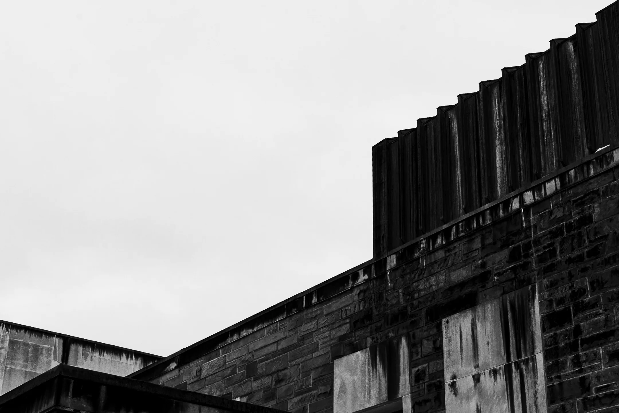 Brand & location — stone building roofline, architectural detail, overcast sky