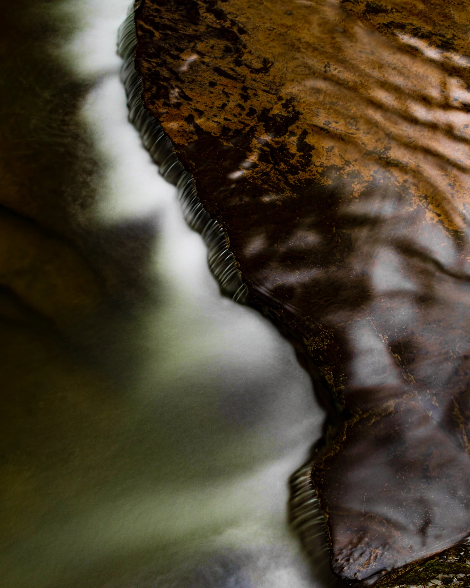Abstract — water flowing over iron-stained rock, long exposure