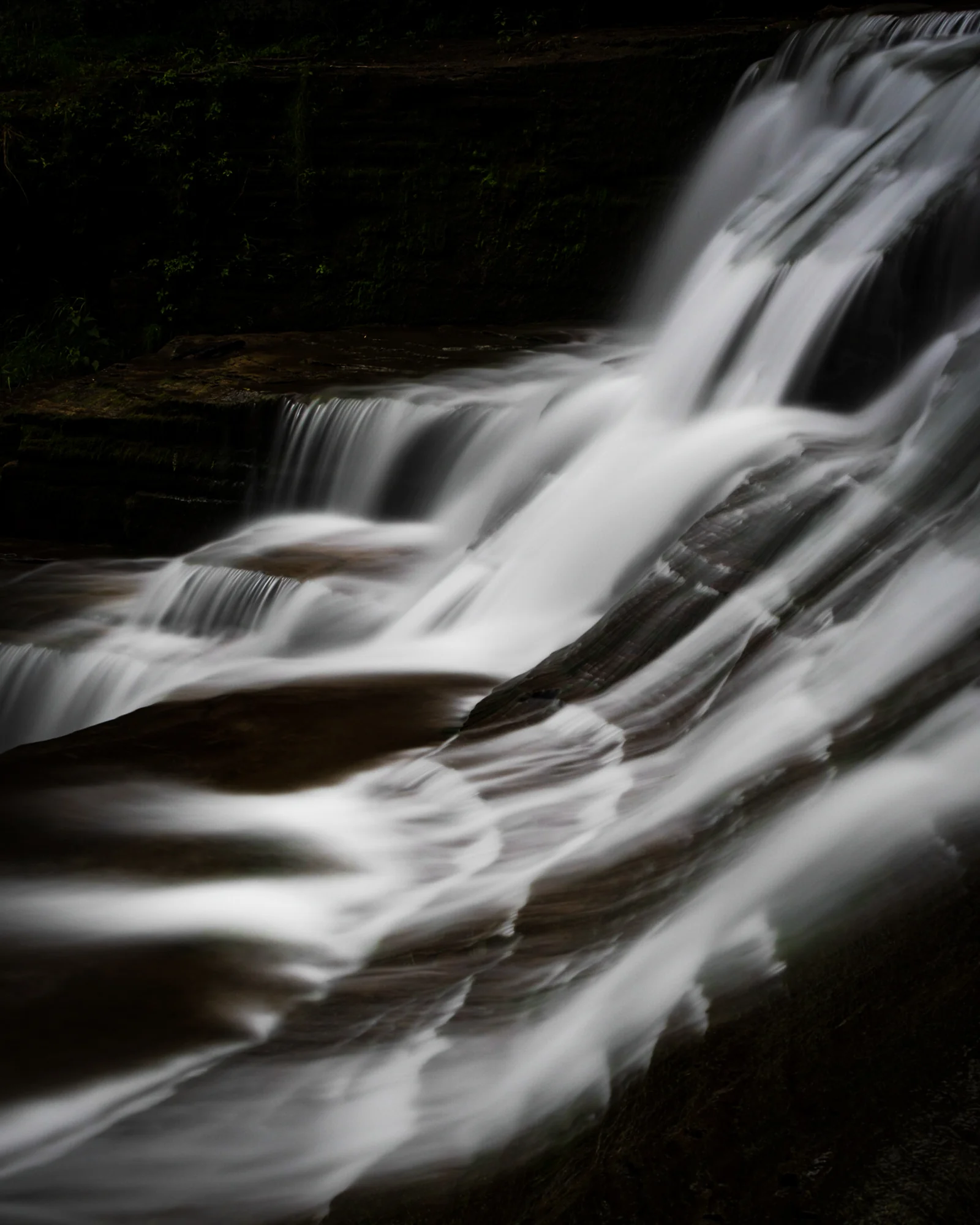 Waterfall cascade over dark rocks, silky long exposure