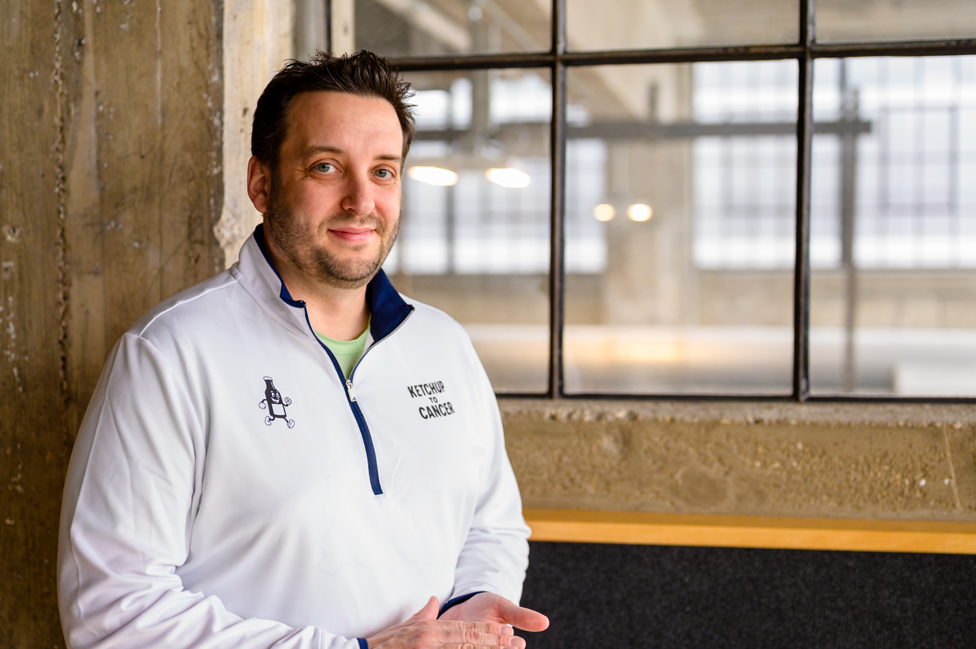 Portrait — man in athletic jacket, industrial window behind him