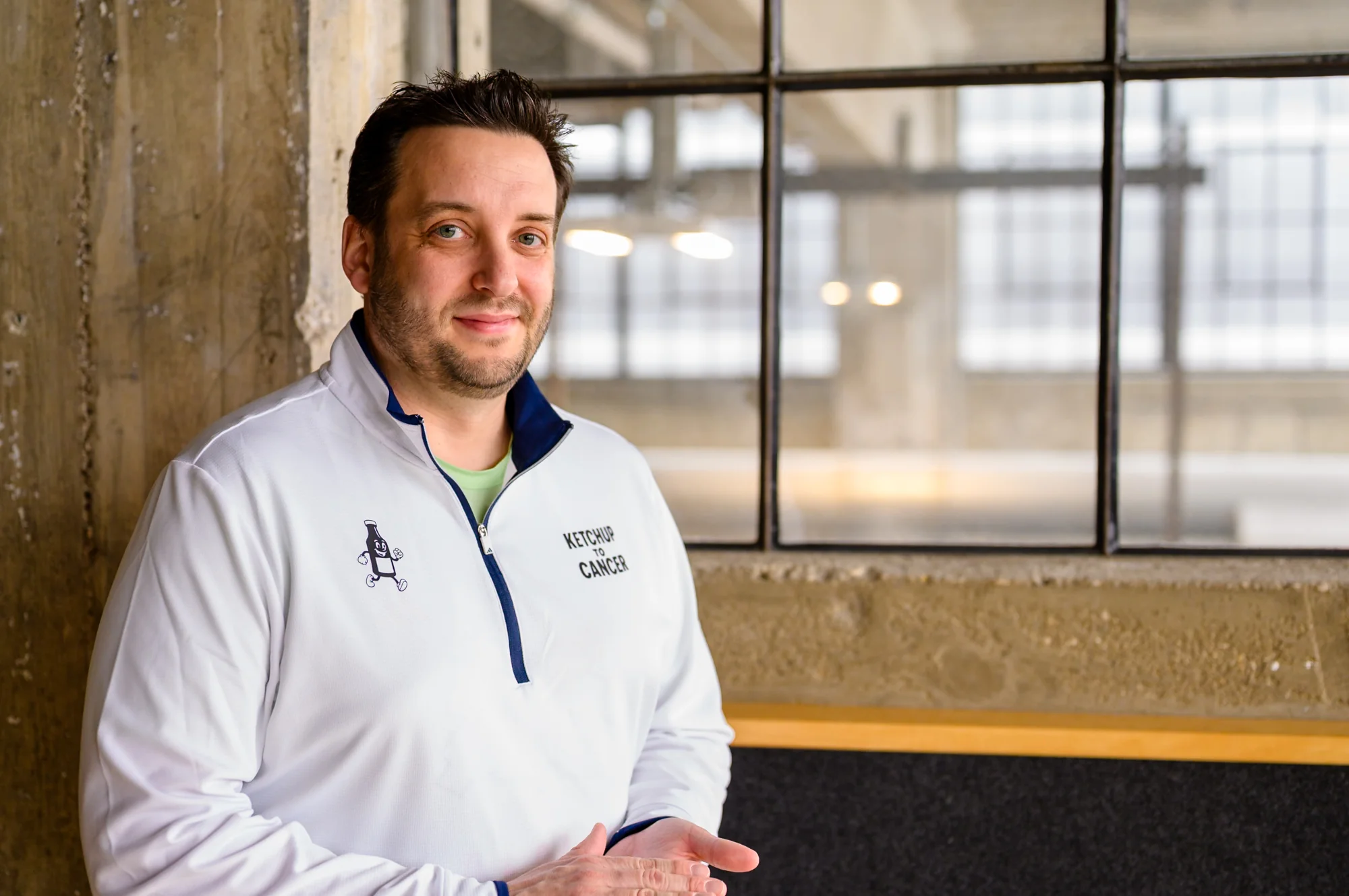 Portrait — man in athletic jacket, industrial window behind him