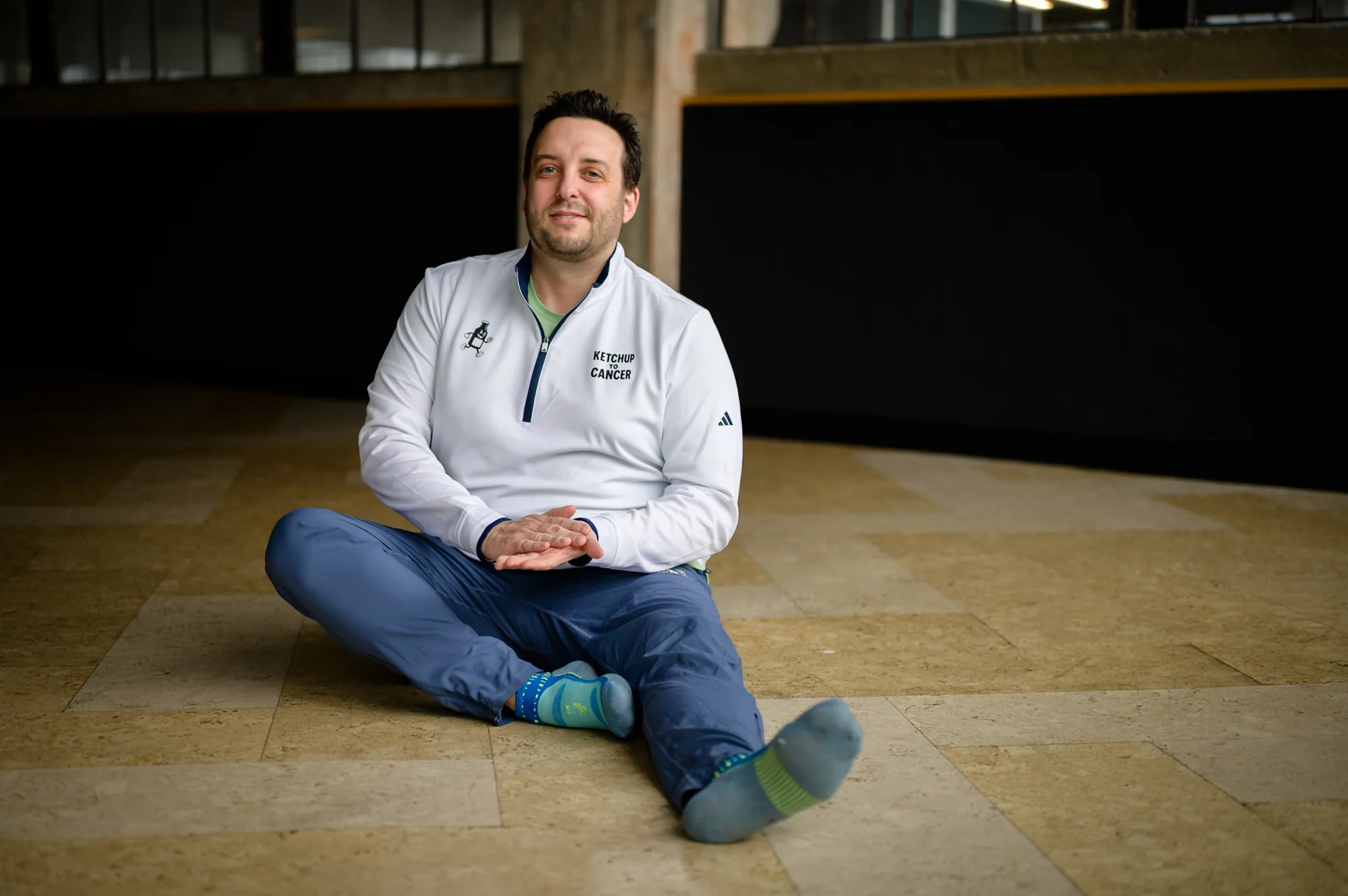 Portrait — man in athletic gear, seated relaxed on stone floor