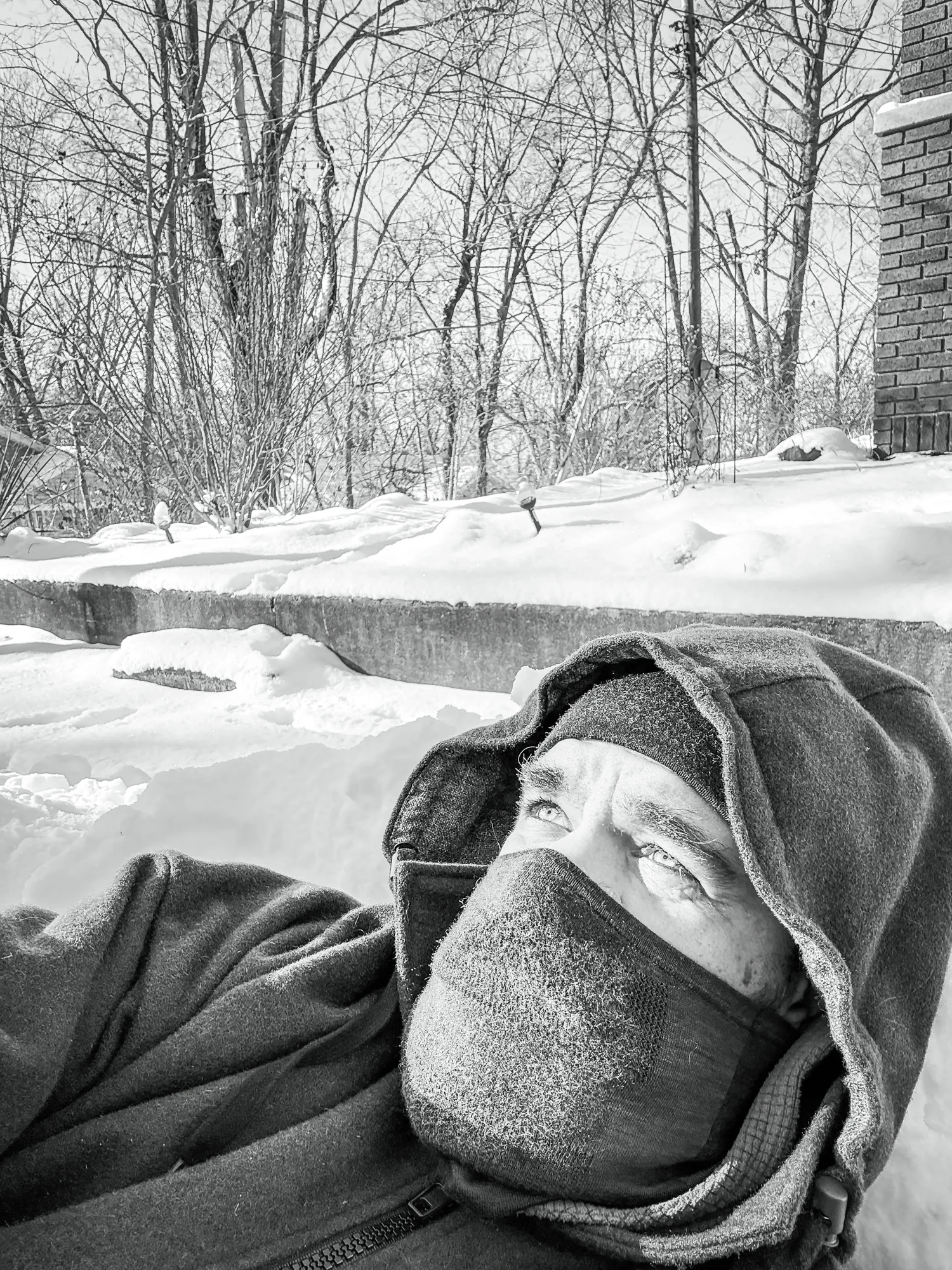 Portrait — person bundled in winter layers, lying in snow