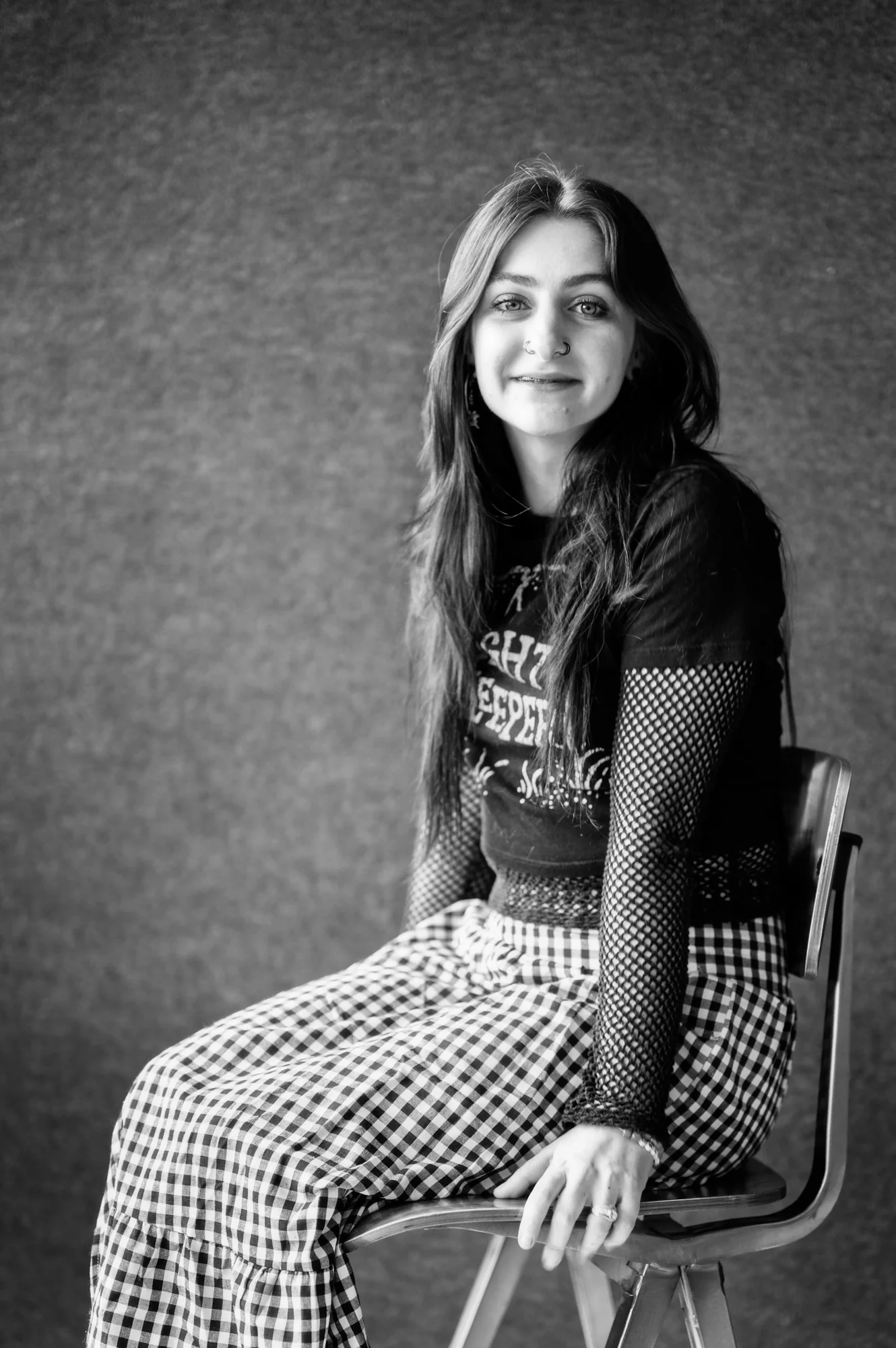 Portrait — woman seated on chair, studio, grey background