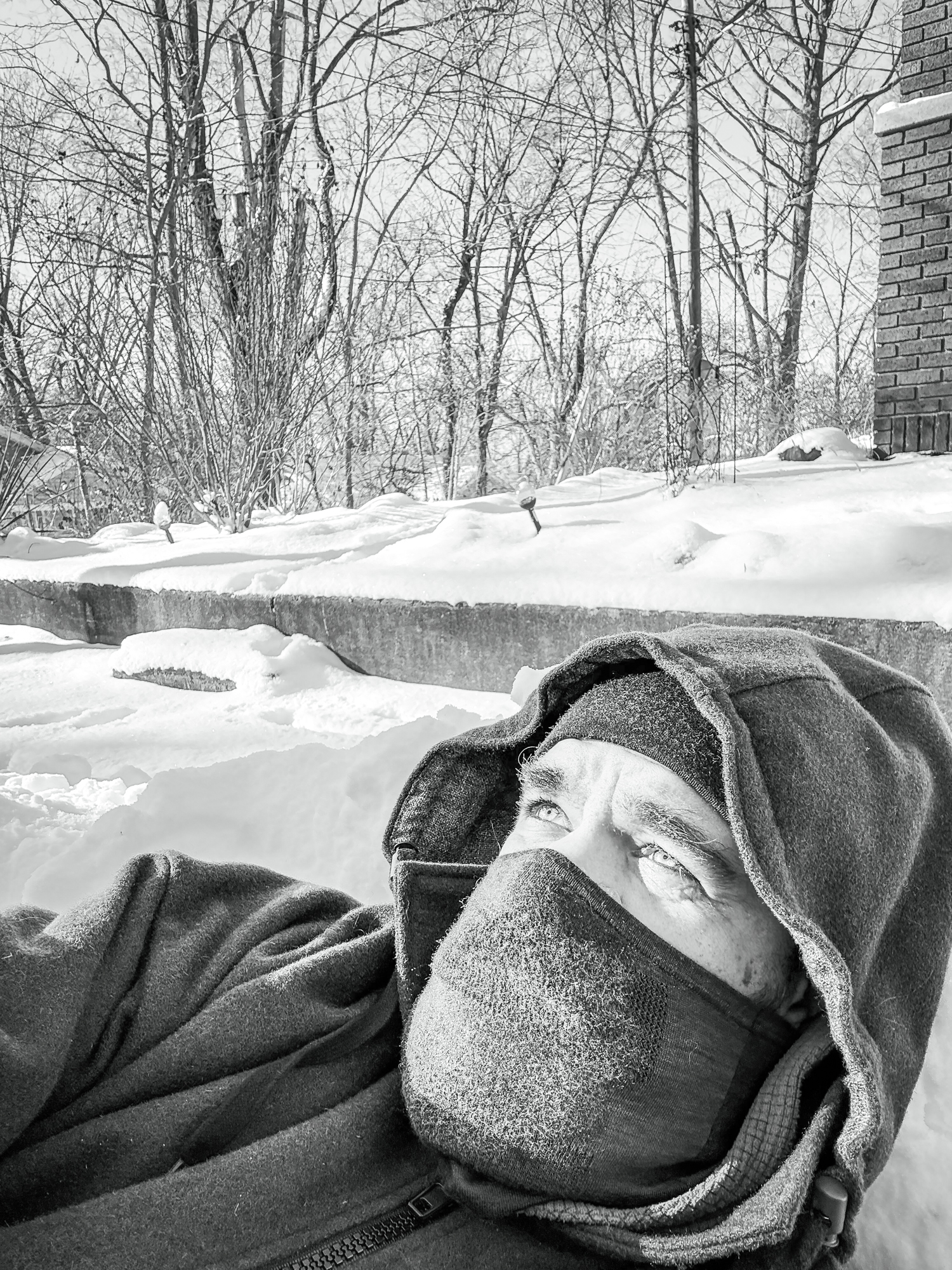 Portrait — person bundled in winter layers, lying in snow