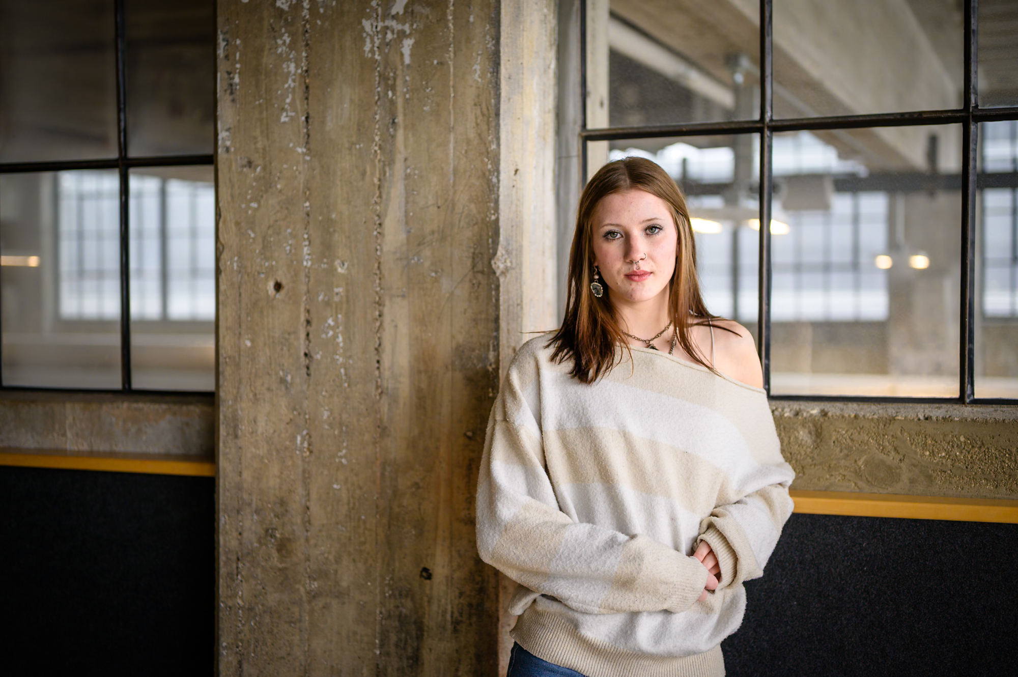 Portrait — woman leaning against concrete pillar, direct gaze