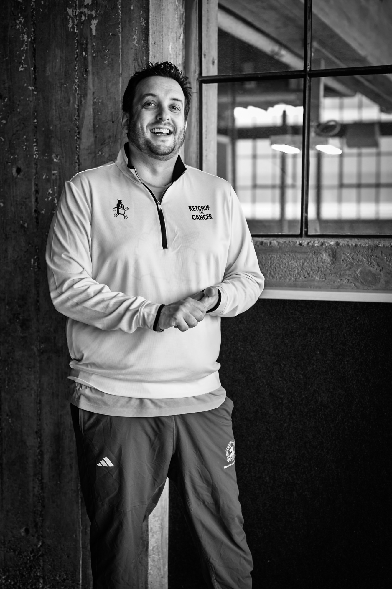 Portrait — man leaning on wooden post, laughing