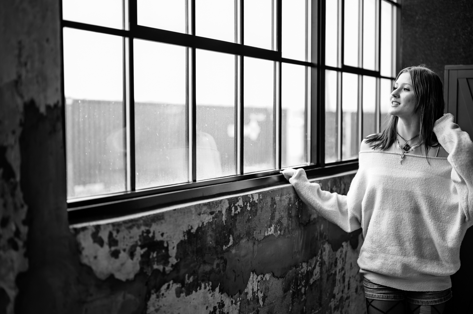 Portrait — woman at tall industrial window, looking out
