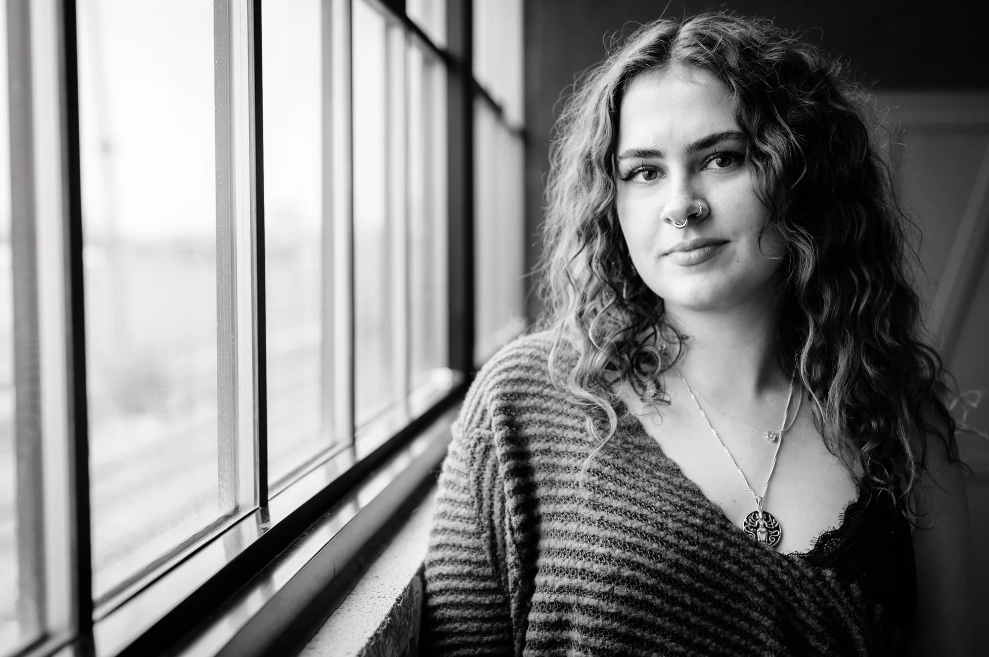 Portrait — woman at window, subtle smile, soft monochrome light